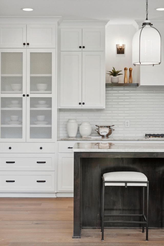 bar with pendant lighting, white cabinets, backsplash, and light wood-type flooring