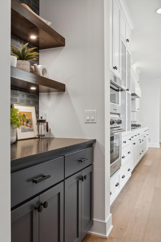 kitchen featuring stainless steel gas stovetop, white cabinets, gray cabinets, and light wood-type flooring