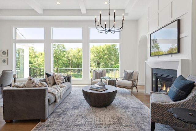 living room featuring beamed ceiling, an inviting chandelier, and hardwood / wood-style floors