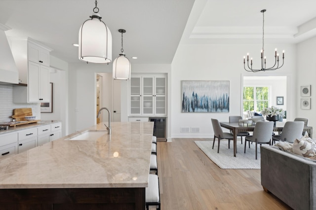 kitchen featuring light hardwood / wood-style floors, decorative light fixtures, a large island with sink, and sink