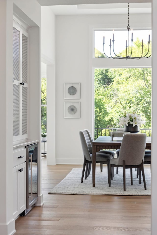 dining room with light hardwood / wood-style flooring, wine cooler, and a notable chandelier