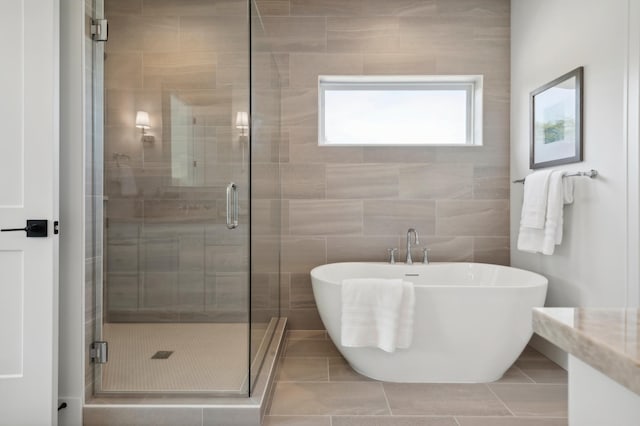 bathroom featuring shower with separate bathtub, tile patterned flooring, and tile walls