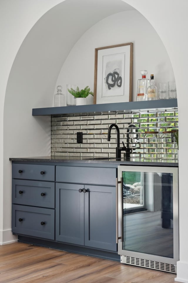 bar with decorative backsplash, wine cooler, hardwood / wood-style floors, and sink