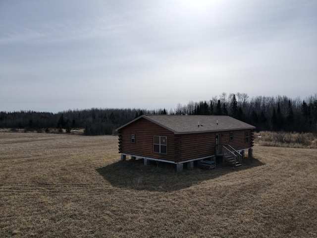 view of home's exterior with a lawn, a forest view, and log siding