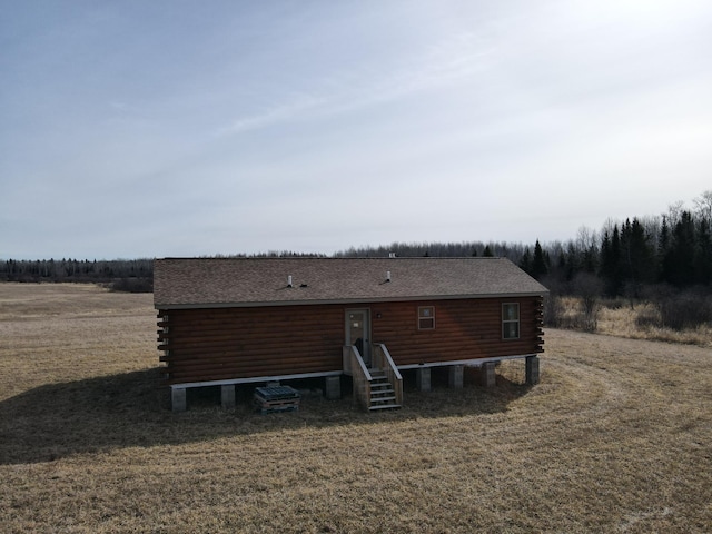 back of property featuring a yard, roof with shingles, and log siding