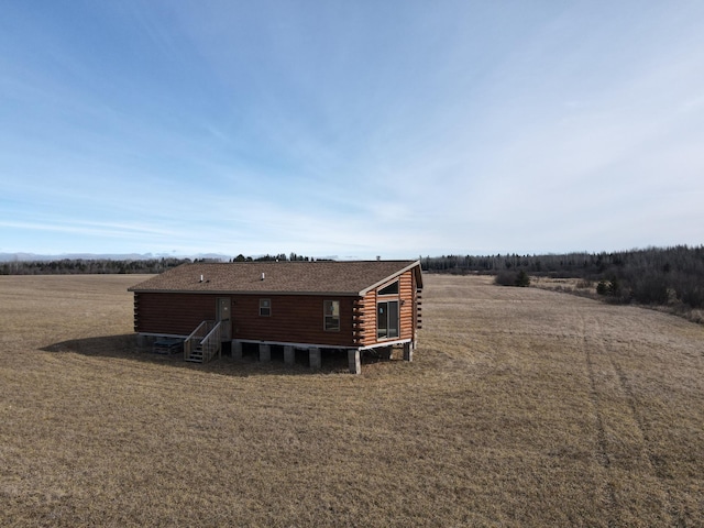 rear view of house featuring a rural view, log exterior, and entry steps