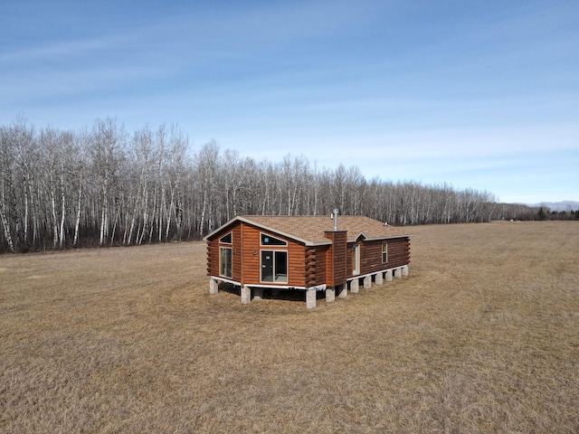 view of side of property with a lawn, roof with shingles, and log siding