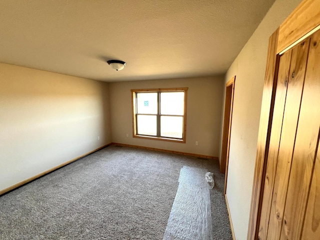 carpeted empty room with a textured ceiling and baseboards