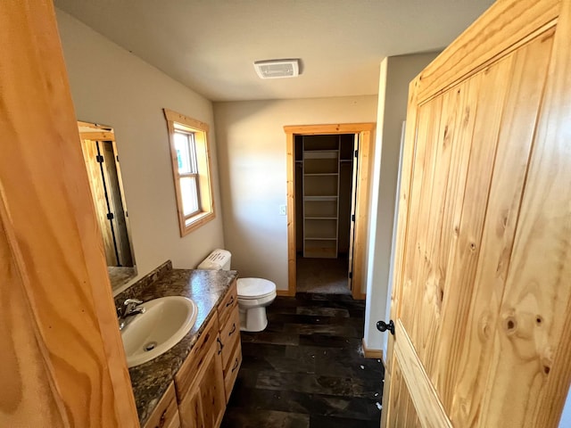 bathroom featuring toilet, visible vents, baseboards, and vanity