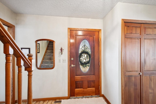 entryway with light colored carpet and a textured ceiling