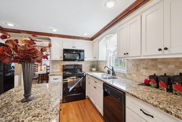 kitchen featuring black appliances, sink, white cabinetry, light hardwood / wood-style flooring, and ornamental molding