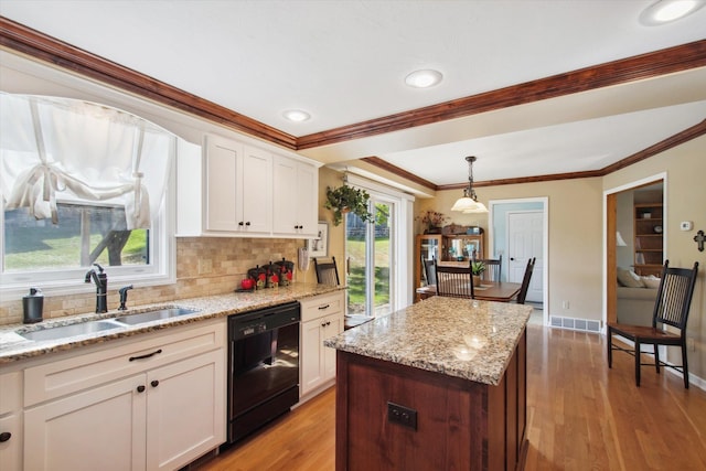 kitchen featuring light hardwood / wood-style floors, pendant lighting, black dishwasher, sink, and white cabinets