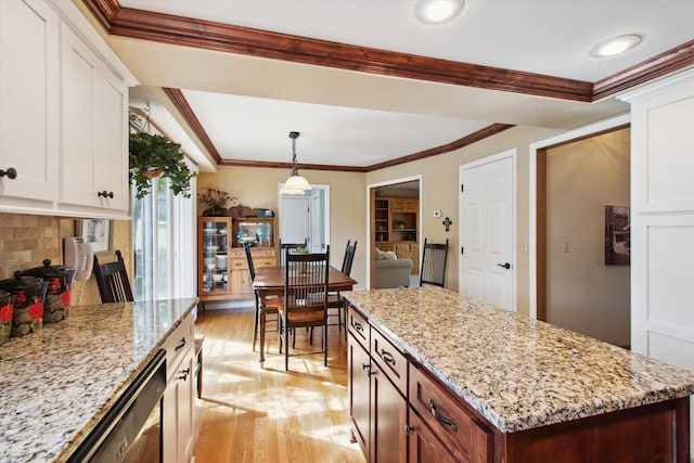 kitchen with pendant lighting, ornamental molding, light hardwood / wood-style flooring, backsplash, and white cabinetry