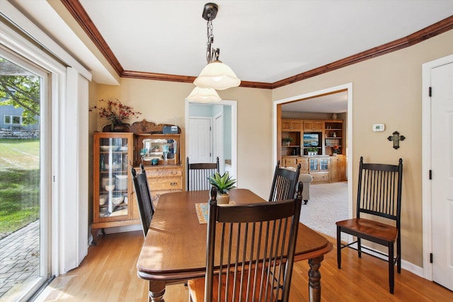 dining space with ornamental molding and light hardwood / wood-style floors