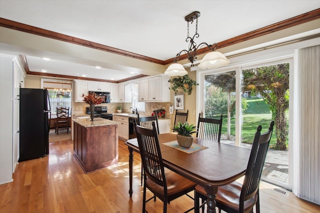 dining room featuring a notable chandelier, ornamental molding, light hardwood / wood-style flooring, and sink