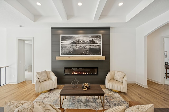 living room with beam ceiling, a fireplace, baseboards, and wood finished floors