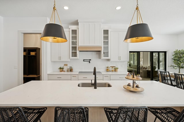 kitchen with decorative light fixtures, backsplash, a kitchen bar, and a sink