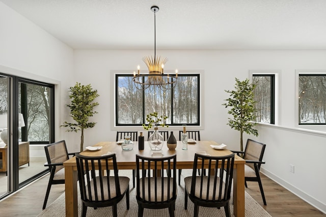 dining space featuring wood finished floors, baseboards, and a chandelier