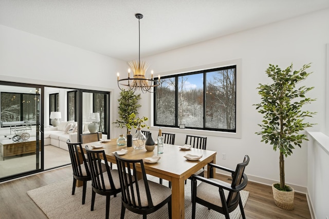 dining space featuring a chandelier, baseboards, and wood finished floors