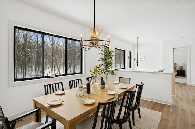 dining space featuring baseboards, plenty of natural light, a notable chandelier, and wood finished floors