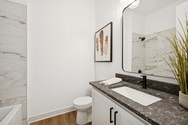 bathroom featuring baseboards, toilet, wood finished floors, and vanity