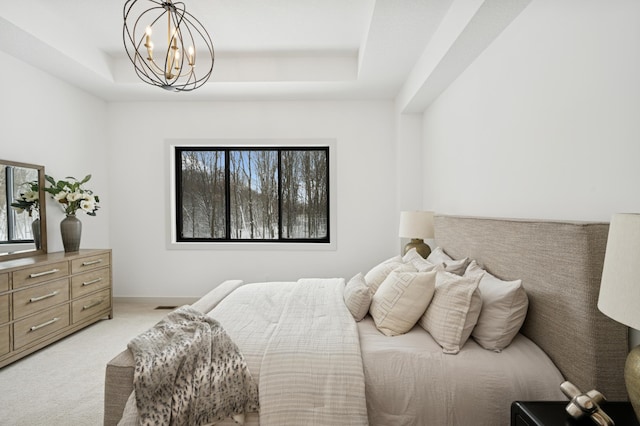 bedroom featuring a tray ceiling, light colored carpet, and a chandelier