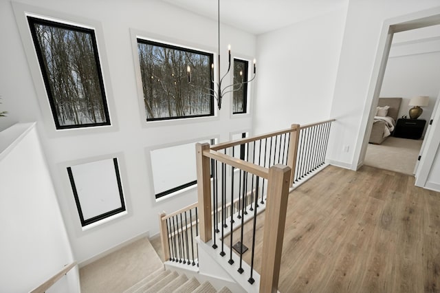 stairway featuring baseboards, an inviting chandelier, and wood finished floors