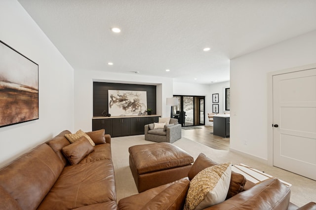 living area with recessed lighting, baseboards, light carpet, and a textured ceiling