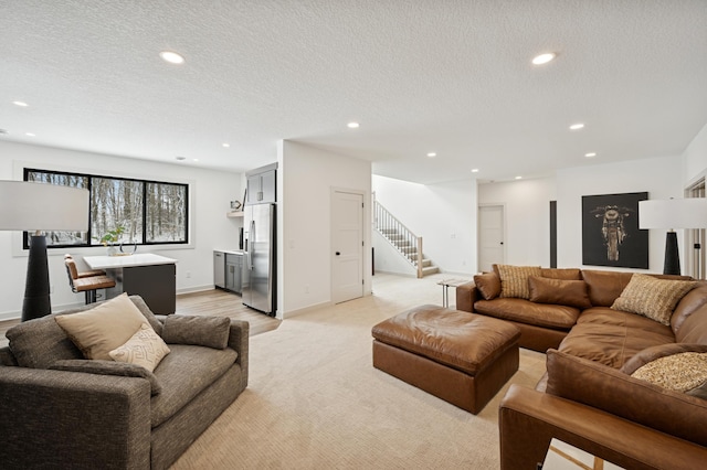 living area with a textured ceiling, recessed lighting, stairway, baseboards, and light colored carpet