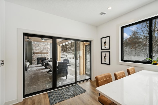 doorway to outside featuring a textured ceiling, wood finished floors, recessed lighting, a stone fireplace, and baseboards