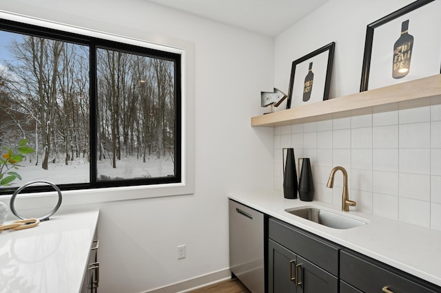 kitchen with a wealth of natural light, decorative backsplash, dishwasher, and a sink