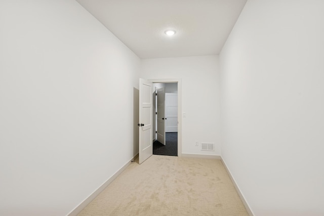 empty room featuring baseboards, visible vents, and light carpet