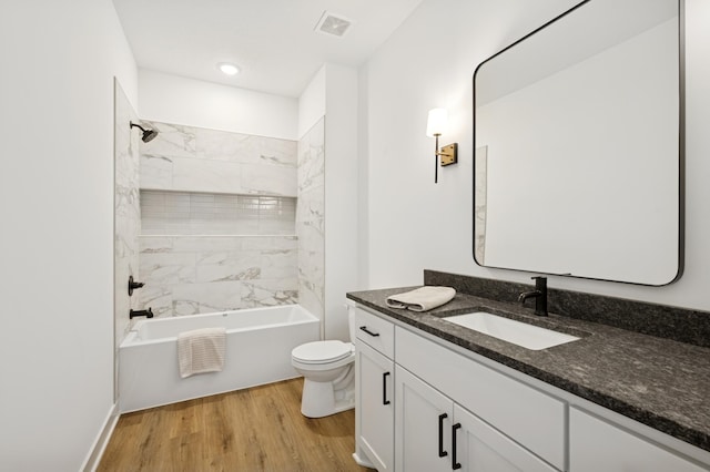 bathroom featuring vanity, wood finished floors, visible vents, bathtub / shower combination, and toilet