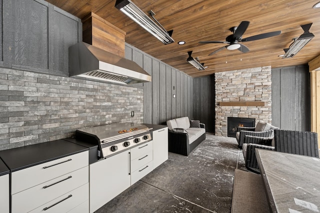 kitchen featuring dark countertops, a fireplace, wooden ceiling, white cabinets, and a ceiling fan
