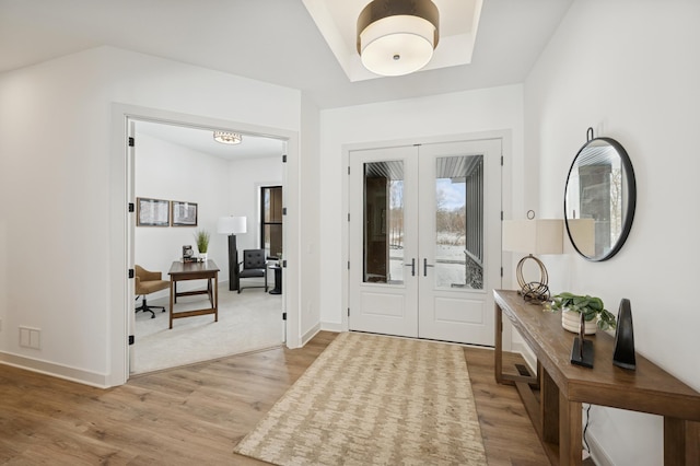 foyer with light wood-style flooring, french doors, and baseboards