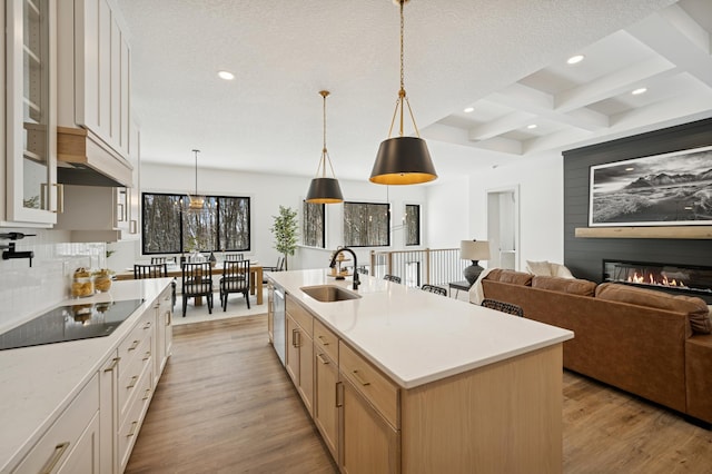 kitchen featuring coffered ceiling, light wood-style flooring, a sink, glass insert cabinets, and beamed ceiling