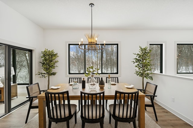 dining room with plenty of natural light, baseboards, an inviting chandelier, and wood finished floors