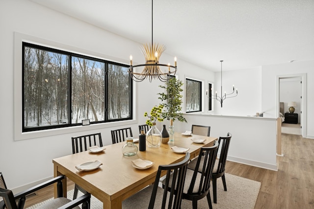 dining space with an inviting chandelier, plenty of natural light, wood finished floors, and baseboards