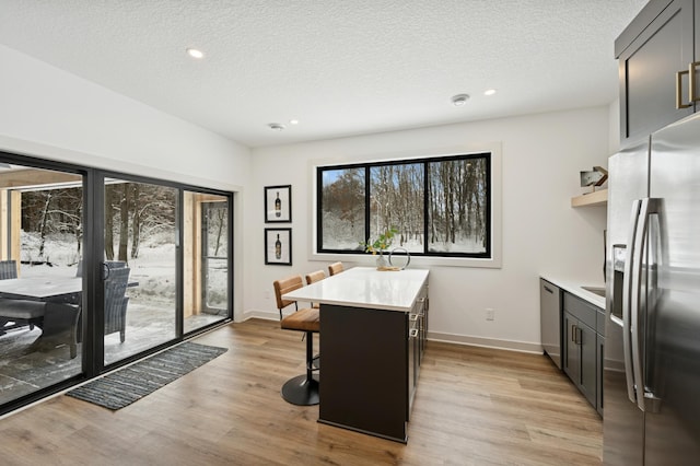 dining room with light wood-style flooring, recessed lighting, baseboards, and a textured ceiling