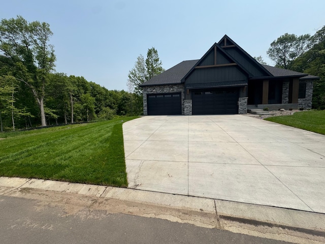 14805 Stutz St NE, Ham Lake, MN 55304 - view of front of house with stone siding, a front yard, an attached garage, and concrete driveway