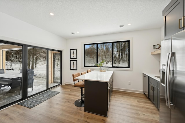 14805 Stutz St NE, Ham Lake, MN 55304 - kitchen featuring stainless steel appliances, light countertops, a breakfast bar, light wood-type flooring, and a textured ceiling
