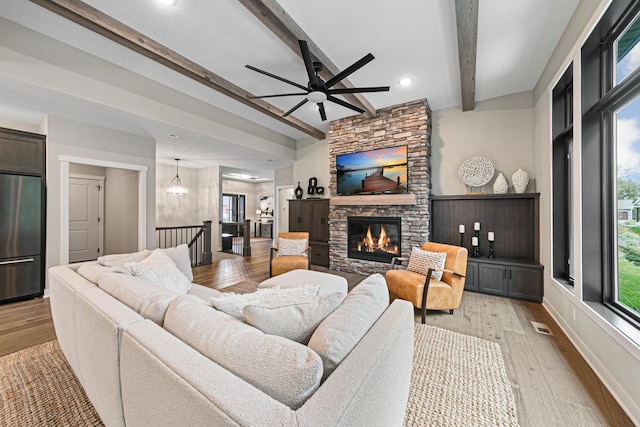 living room with light hardwood / wood-style floors, beam ceiling, a fireplace, and ceiling fan