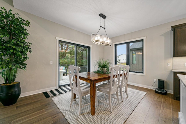 dining area featuring a notable chandelier, plenty of natural light, and dark hardwood / wood-style flooring