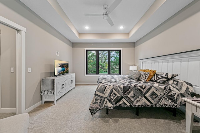 carpeted bedroom featuring ceiling fan and a raised ceiling