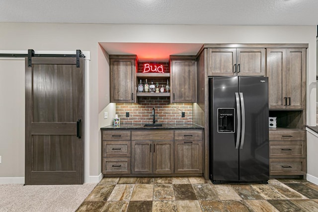 kitchen with decorative backsplash, stainless steel refrigerator with ice dispenser, a textured ceiling, and a barn door