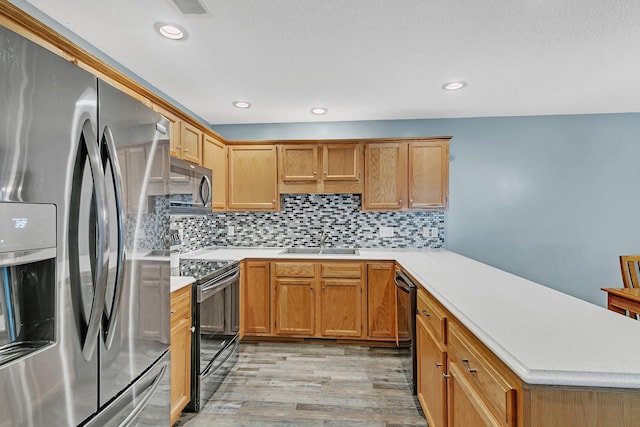 kitchen with sink, black appliances, decorative backsplash, and light wood-type flooring