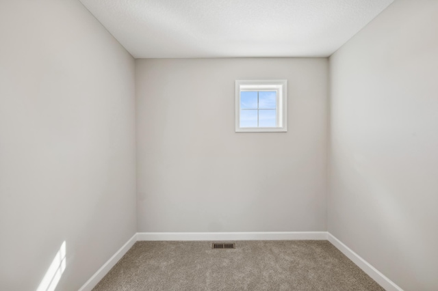 unfurnished room with carpet flooring, visible vents, and baseboards