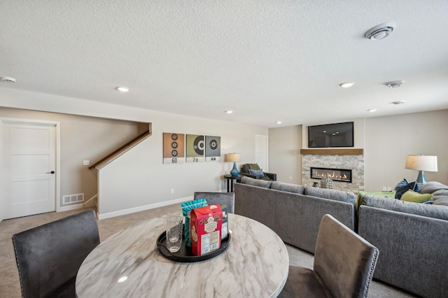 dining area with a fireplace, light colored carpet, visible vents, a textured ceiling, and baseboards