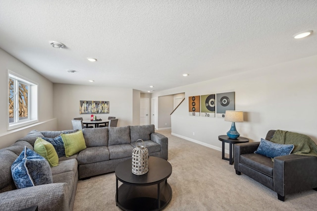 living room featuring recessed lighting, light colored carpet, a textured ceiling, and baseboards