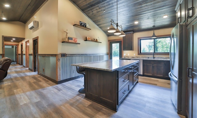 kitchen featuring wood ceiling, hanging light fixtures, a kitchen island, stainless steel refrigerator, and an AC wall unit